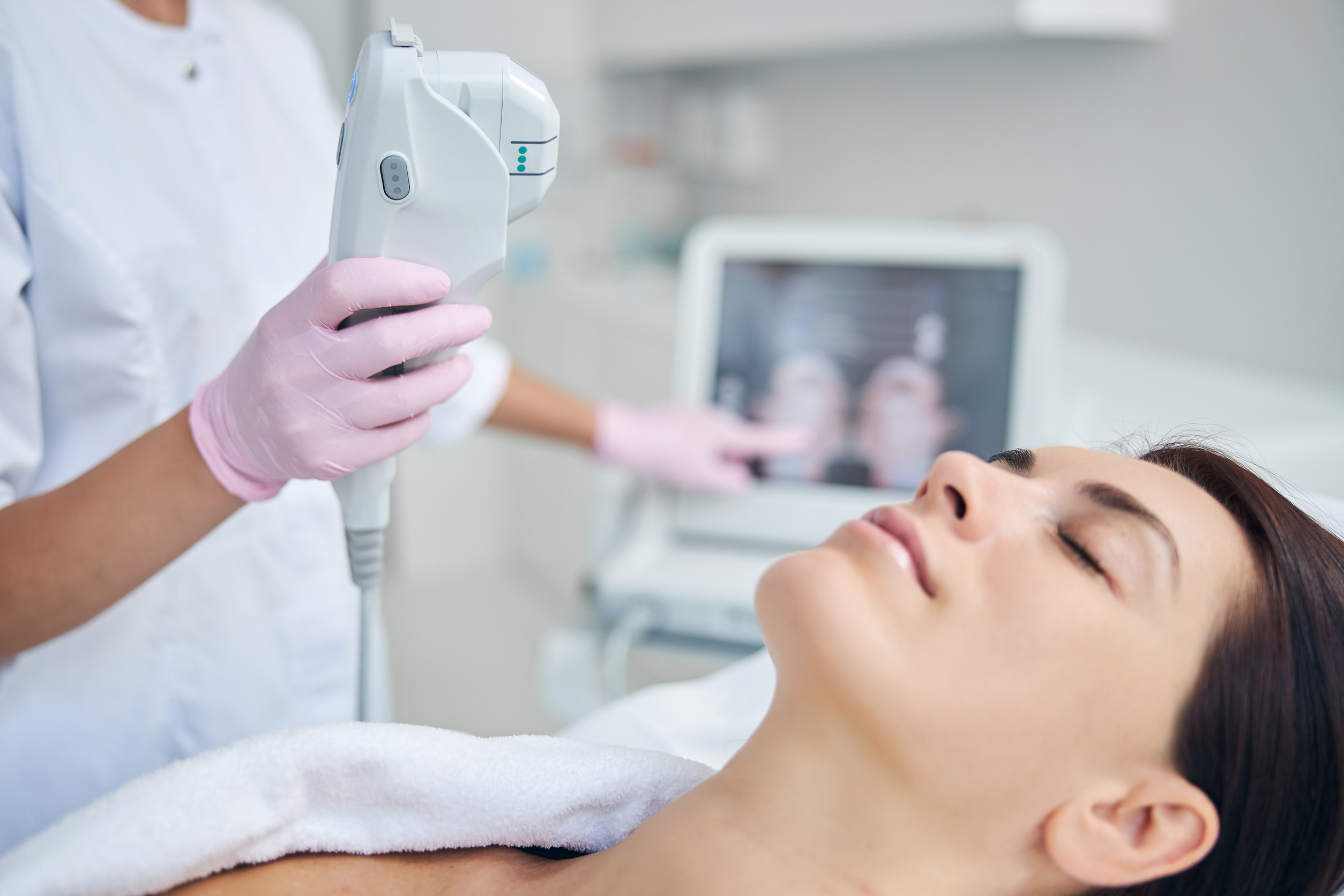 A practitioner performing a precision skin treatment on a client, guided by real-time imaging on a connected device.